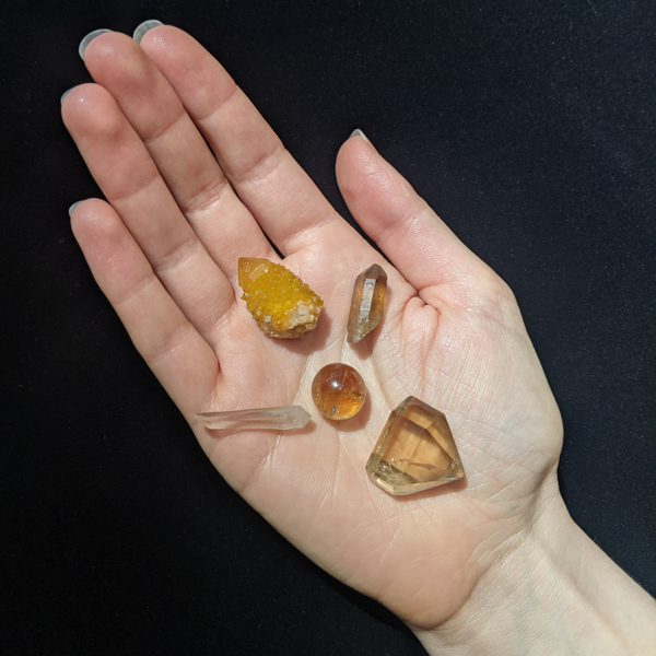 Hand holding five citrine crystals.
